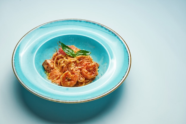 Pâtes appétissantes aux tomates et crevettes, parmesan dans un bol bleu sur une surface grise. cuisine italienne