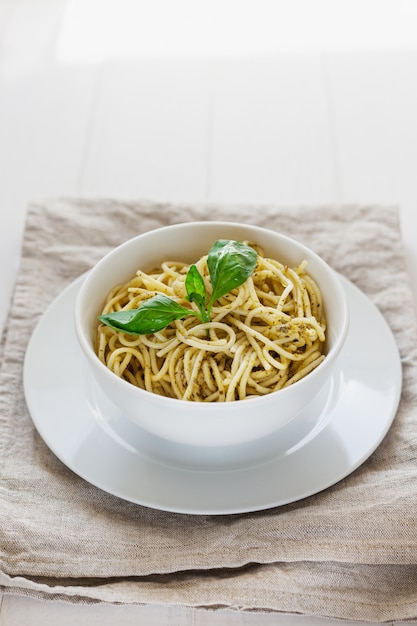 Pâtes au pesto dans une assiette blanche sur fond clair