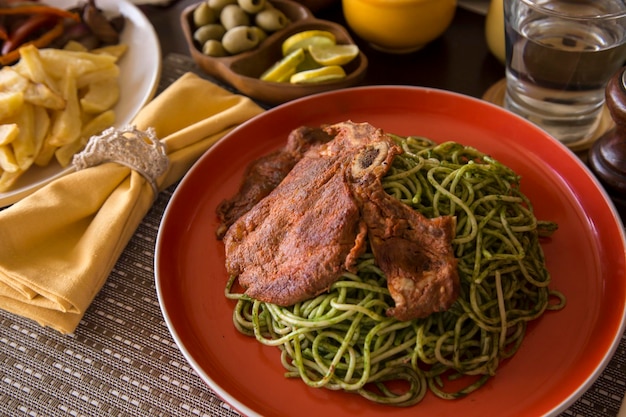 Pâtes au pesto vert avec côtelette de porc restaurant gastronomique péruvien réconfortant fait maison