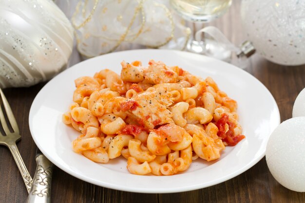 Pâtes au poisson et à la sauce tomate sur une plaque blanche sur du bois brun