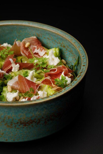 Pâtes au prosciutto et courgettes frites sur fond noir