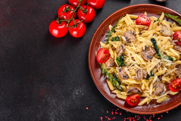 Pâtes aux champignons, fromage, épinards, rukkola et tomates cerises. Plat italien, culture méditerranéenne