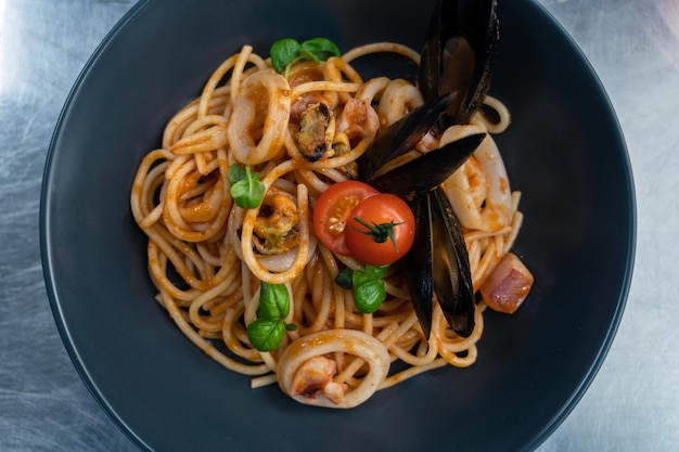 Pâtes aux fruits de mer aux moules au basilic et tomate en plaque noire