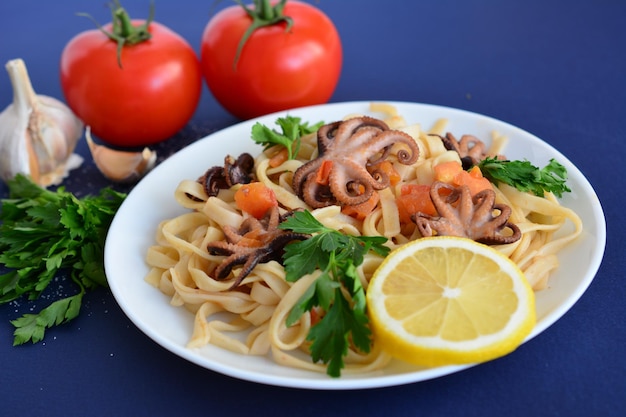 pâtes aux fruits de mer, poulpe et tomates sur la plaque blanche isolée