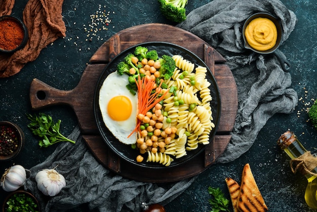 Pâtes aux légumes et œuf au plat sur une assiette en pierre noire Bol Bouddha Vue de dessus Espace libre pour le texte