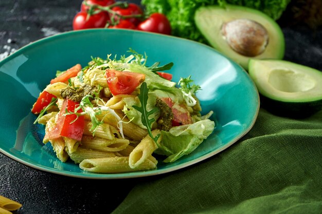 Pâtes aux légumes tomates et pesto dans une assiette sur fond sombre Salade de pâtes