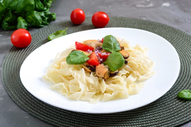 Pâtes aux moules, tomates sur une plaque blanche sur une table en bois