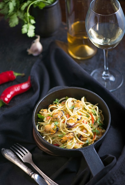 Pâtes aux moules, un verre de vin blanc fond sombre