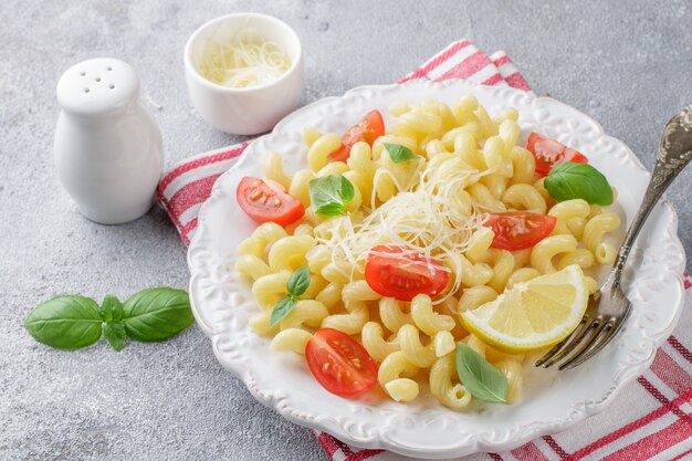 Pâtes aux tomates, basilic et fromage sur une assiette blanche, dîner italien traditionnel,