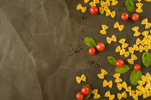 Pâtes aux tomates cerises et épinards sur fond noir à plat