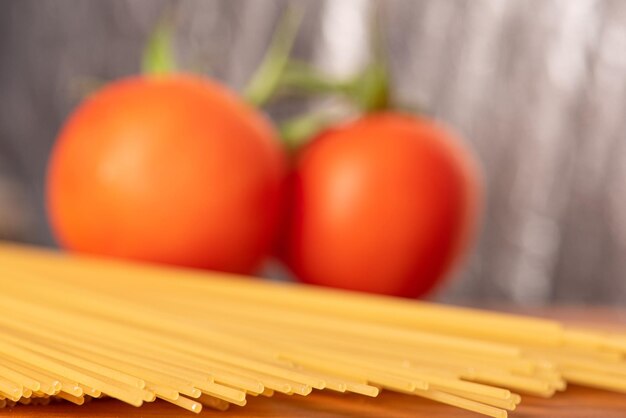 Pâtes beaux détails de tomates rouges et de brins de spaghettis crus sur une mise au point sélective en bois rustique