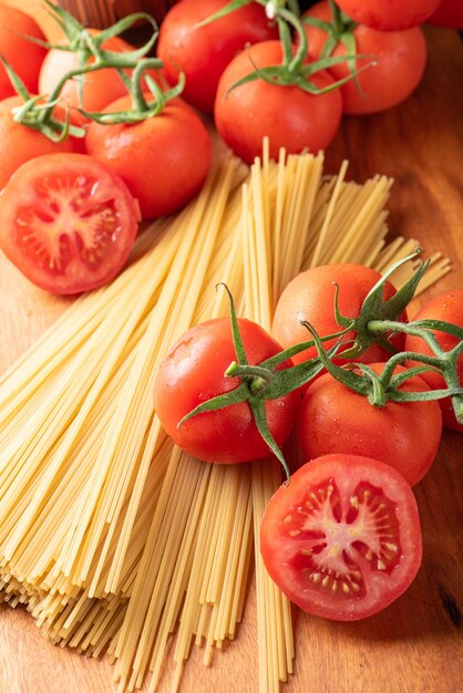 Pâtes beaux détails de tomates rouges et de brins de spaghettis crus sur la vue de dessus en bois rustique