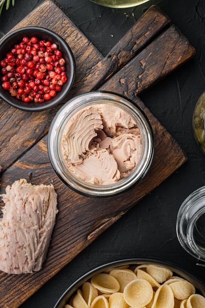 Pâtes de blé entier avec tomates séchées et ingrédients de thon sur fond noir, plat