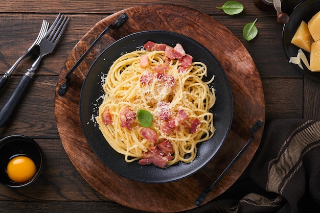 Pâtes à la carbonara Spaghetti aux œufs de pancetta, fromage parmesan et sauce à la crème sur fond de table en bois noir foncé Cuisine et plat traditionnels italiens Pâtes alla carbonara Vue de dessus