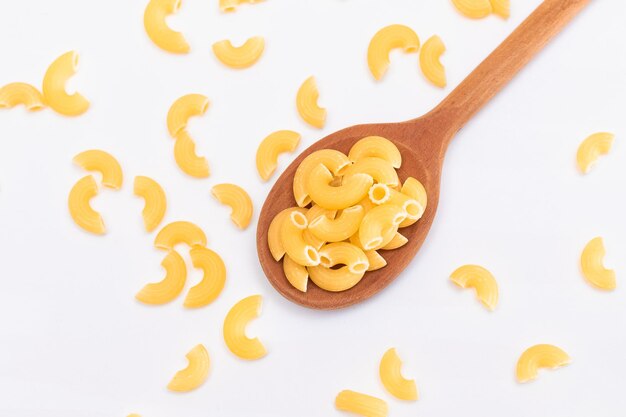 Pâtes de chifferi rigati non cuites dans une cuillère en bois sur fond blanc