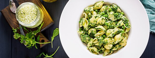 Pâtes conchiglie aux épinards et au pesto de pois verts. Cuisine italienne. Nourriture végétalienne. Bannière. Vue de dessus