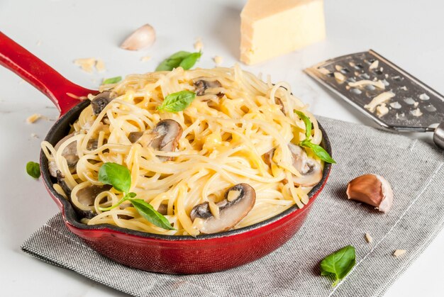 Pâtes crémeuses aux champignons avec fromage et basilic, dans une poêle à frire portionnée