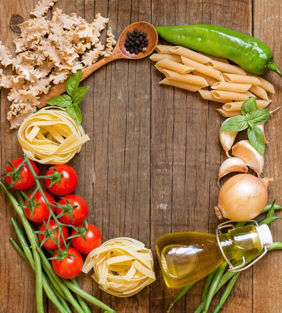 Pâtes, crudités, huile et huile de copie sur l'ancienne vue de dessus de table en bois