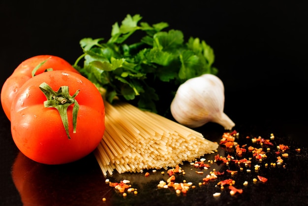 Pâtes crues aux légumes et épices macaroni ingrédients sur fond noir