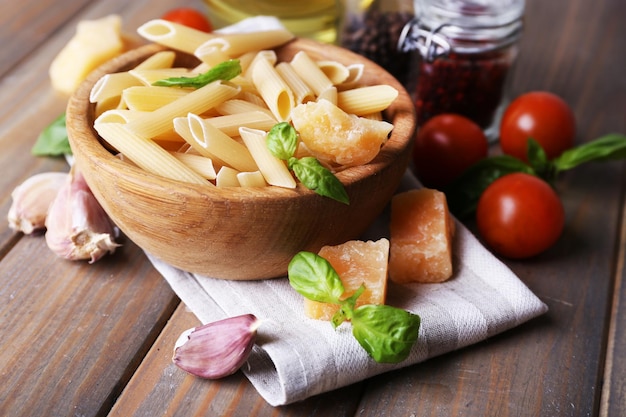 Pâtes crues dans un bol avec du fromage et des légumes sur la table en gros plan