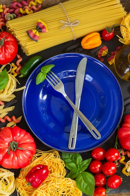 Pâtes crues avec ingrédients et assiette bleue