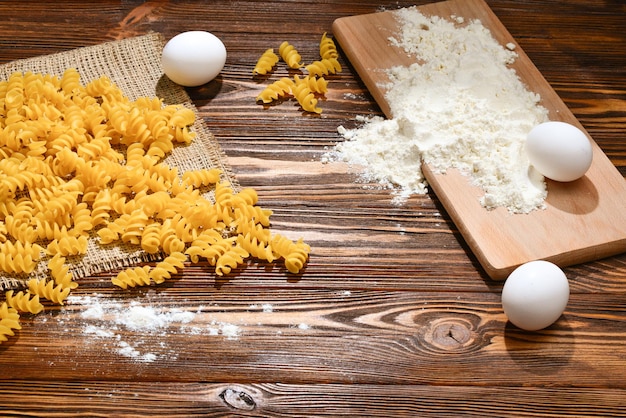 Pâtes crues et ingrédients pour pâtes sur fond de bois