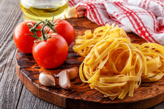 Pâtes crues et tomates sur une planche à découper