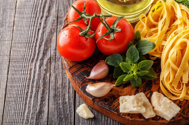 Pâtes crues et tomates sur une planche à découper