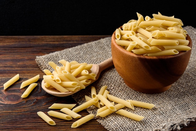 Pâtes dans un bol en bois sur fond de bois foncé.