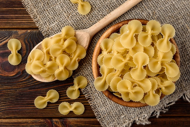 Pâtes dans un bol en bois sur fond de bois foncé.