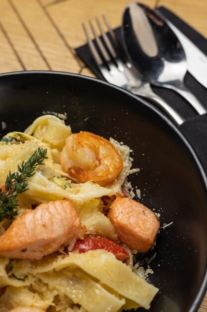 Photo des pâtes délicieuses avec des crevettes, des tomates et du saumon