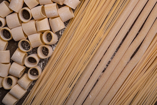 Les pâtes faites à la main sur fond marron font l'objet de cette photo Les nouilles sont de différentes formes et