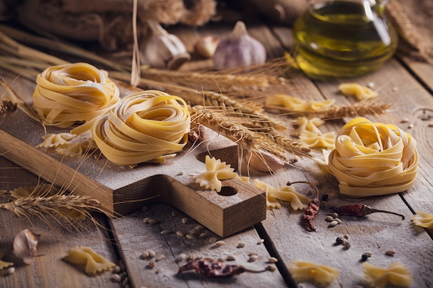 Pâtes faites maison crues avec de la farine et des épices sur le fond rustique. Nouilles non cuites.