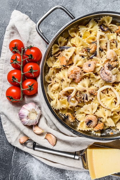 Pâtes farfales aux fruits de mer dans une poêle. poulpe, crevette, calmar, pétoncle et moules. Vue de dessus