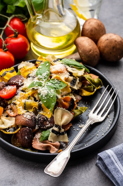 Pâtes Farfalle aux champignons, basilic, tomates et sauce à la crème. Cuisine traditionnelle italienne. un plat méditerranéen