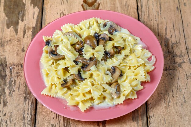 Pâtes Farfalle dans une sauce crémeuse aux champignons dans une assiette sur une table en bois