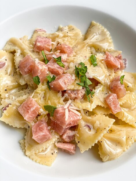 pâtes farfelle à la carbonara avec saucisse de jambon sur plaque blanche