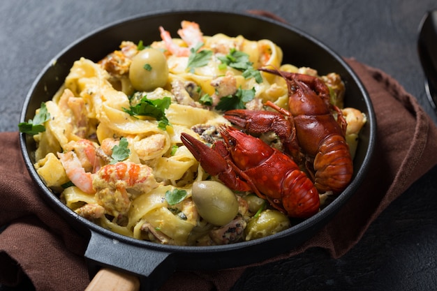 Pâtes fettuccine aux fruits de mer avec écrevisses, crevettes de poulpe, sur poêle en pierre. Plat gourmand