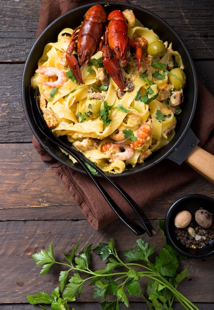 Pâtes fettuccine aux fruits de mer avec écrevisses, crevettes de poulpe, sur poêle en pierre. Plat gourmand