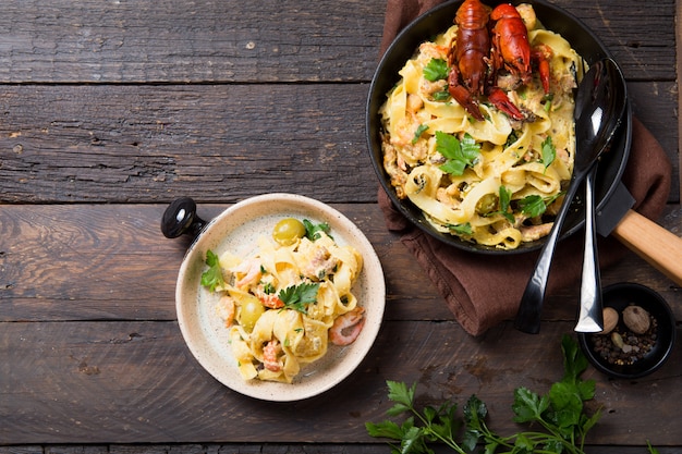 Pâtes fettuccine aux fruits de mer avec écrevisses, crevettes de poulpe, sur poêle en pierre. Plat gourmand