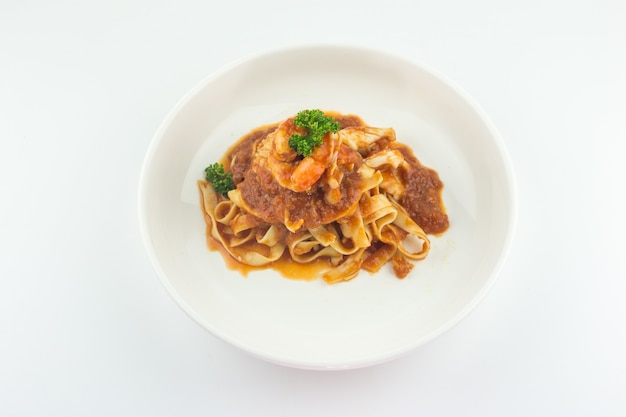 Pâtes Fettuccine Bolognaise avec sauce tomate et crevettes en plaque blanche sur fond blanc