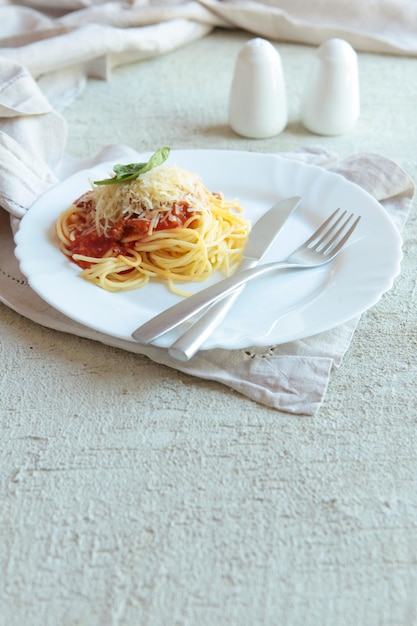 Pâtes Fettuccine Bolognaise avec sauce tomate sur plaque blanche. Carlic et sel et tomates sur fond de béton avec des serviettes en lin.
