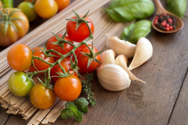 Pâtes fettuccine crues, légumes et herbes sur fond de bois