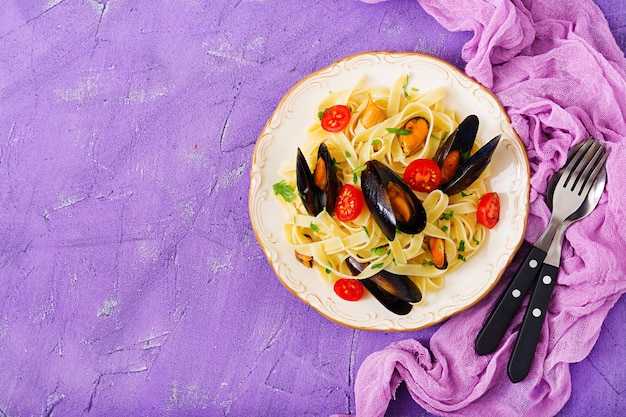 Pâtes fettuccine de fruits de mer aux moules sur fond violet