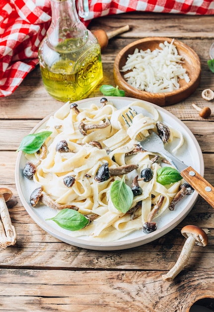 Pâtes fettuccine italiennes crémeuses faites maison avec des champignons au miel Servies sur un fond de bois rustique