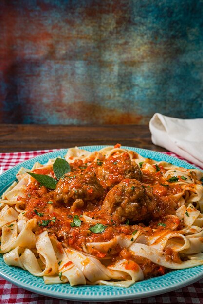 Pâtes Ou Fettuccine Avec Sauce Tomate Et Boulettes De Viande Dans Une Assiette Rustique Sur Une Nappe à Carreaux.