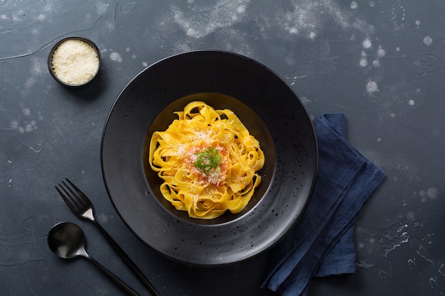 Pâtes fettuccine avec sauce traditionnelle italienne Passat et parmesan en plaque noire sur surface sombre