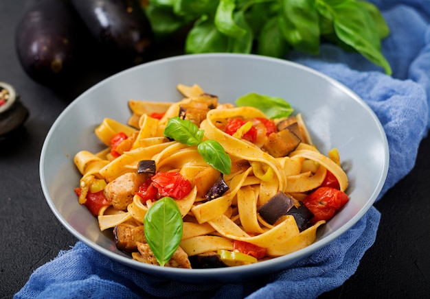 Pâtes Fettuccine avec tomate, aubergine et filet de poulet dans un bol.