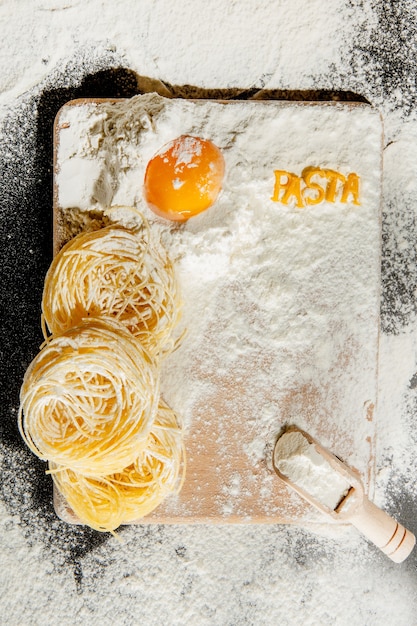 Les pâtes fraîchement cuites reposent sur une surface sombre saupoudrée de farine. Pâtes italiennes. Tagliatelles