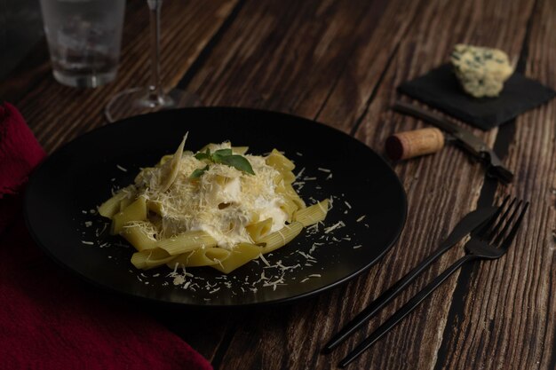 Pâtes Fromage macaroni penne au basilic sur le dessus Plaque noire sur table en bois Mise au point sélective